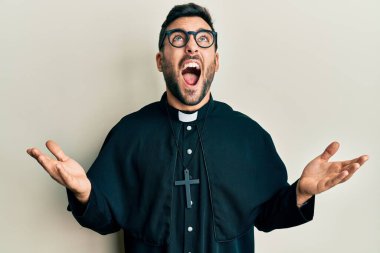 Genç İspanyol rahip, beyaz arka planda öfkeli ve kızgın bir şekilde bağırıyor öfkeyle bağırıyor.. 