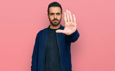 Günlük kıyafetler giyen genç İspanyol adam avucunun içi gibi şarkı söylemeyi kesiyor. Yüzünde olumsuz ve ciddi bir jest olan uyarı ifadesi. 