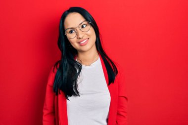 Güzel İspanyol bir kadın, burun piercingli, sıradan görünümlü ve gözlüklü, yüzünde gülümsemeyle yan yana bakan, doğal bir ifade. Kendinden emin gülen. 