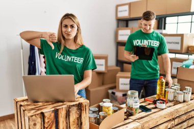 Bağışlarda gönüllü tişört giyen genç kadın ve erkek kızgın suratlı, olumsuz işaretli baş parmakları aşağıda, reddedilme konsepti var. 