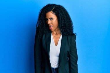 Orta yaşlı Afro-Amerikan kadın iş kıyafetleri içinde kameraya seksi bir ifadeyle bakıyor, neşeli ve mutlu bir yüzle.. 