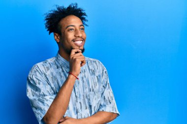 Young african american man with beard wearing casual clothes looking confident at the camera with smile with crossed arms and hand raised on chin. thinking positive. 