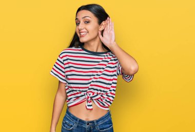 Günlük kıyafetler giyen, ağzı kulaklarında gülümseyen genç İspanyol kız dedikoduları ve dedikoduları dinliyor. Sağırlık kavramı. 