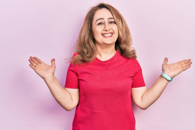 Orta yaşlı beyaz kadın, günlük kıyafetler giyip gülümseyerek avuçlarını açıyor, sunuyor ve reklam karşılaştırması yapıyor ve dengeyi sağlıyor. 