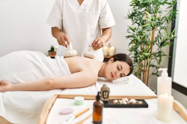 Bitkisel kese alan genç bir kadın güzellik merkezinde Thai masajı yapıyor..