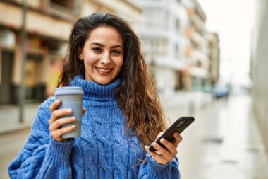 Genç İspanyol kadın akıllı telefon kullanıyor. Şehirde kahve içiyor..