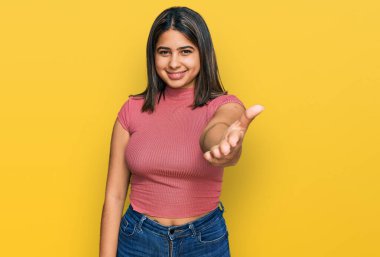 Gündelik tişört giyen genç İspanyol kız selamlaşma ve hoş geldin demek için dostça el sıkışma teklif ediyor. başarılı iş. 