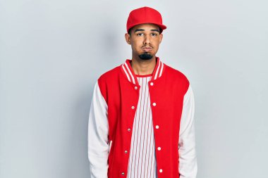 Beyzbol forması giyen genç Afro-Amerikan adam komik suratlı yanak şişiriyor. Havayla şişmiş ağız, çılgın bir ifade.. 