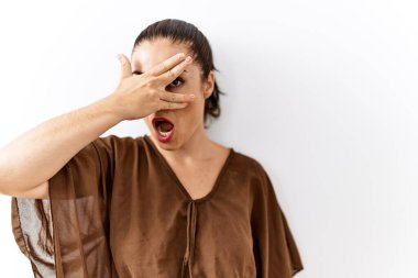 Genç esmer kadın izole edilmiş arka planda duruyor. Şoka giriyor. Yüzü ve gözleri kapanıyor, utangaç ifadesiyle parmaklarından bakıyor.. 