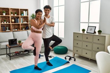 Gülümseyen genç Latin çift evde mutlu yoga pozu veriyor..