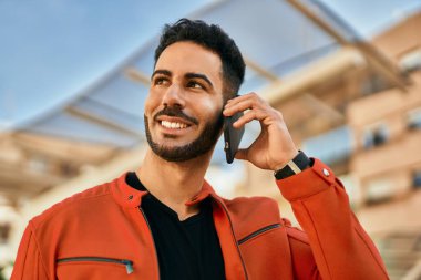 Genç İspanyol adam gülümsüyor. Şehirdeki akıllı telefondan konuşuyor..
