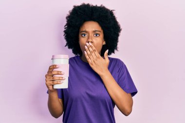 Genç Afro-Amerikalı kadın elinde kahveyle ağzını kapatıyor, şaşırmış ve hata yapmaktan korkuyor. şaşırmış ifade 