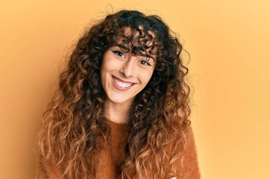 Gündelik kıyafetler giyen, kollarını kavuşturup kameraya gülümseyen genç İspanyol kız. pozitif kişi. 