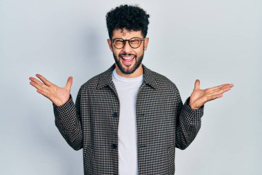 Gözlüklü genç Arap adam başarı için çıldırıyor ve çıldırıyor kollarını kaldırıyor ve gözleri kapalı heyecanla bağırıyor. Kazanan konsept 