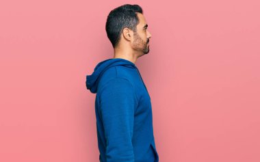 Latin kökenli genç adam rahat bir görünüm takınıyor, rahat bir görünüm takınıyor, kendine güvenen bir gülümsemeyle.. 