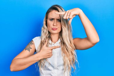 Güzel sarışın kadın resim çerçevesi jesti yapıyor elleri şüpheci ve gergin, sorun yüzünden surat asıyor. negatif kişi. 