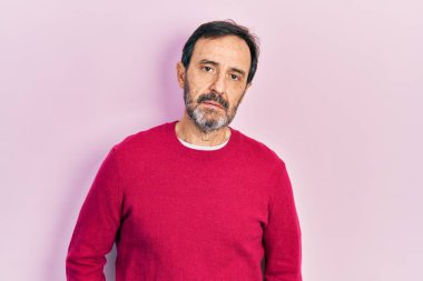 Orta yaşlı İspanyol bir adam gündelik kıyafetler giyiyor ve yüzünde ciddi bir ifadeyle rahatlıyor. Basit ve doğal bir şekilde kameraya bakıyorsun.. 