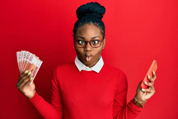 Joven Mujer Afroamericana Usando Smartphone Con Billetes Noruegos Haciendo Cara —  Fotos de Stock