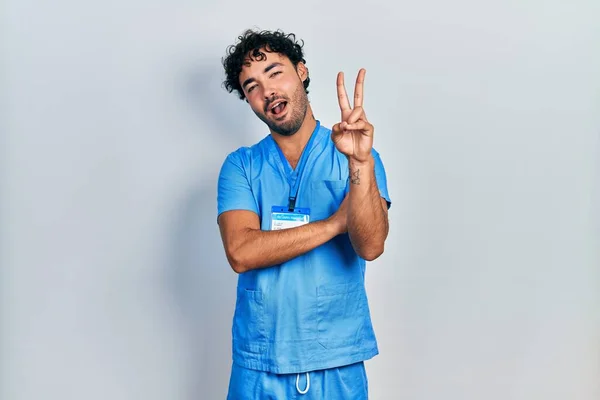 Молодий Іспаномовний Чоловік Блакитній Формі Медсестри Посміхається Щасливим Обличчям Підморгнутим — стокове фото