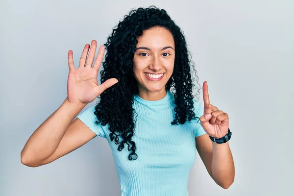 若いですヒスパニック女性とともに巻き毛を身に着けていますカジュアルブルーTシャツ表示され 指番号6で指摘しながら 自信と幸せ — ストック写真