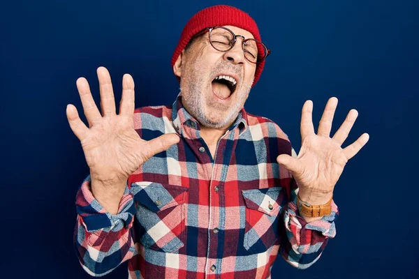 ウールキャップでヒップルックを身に着けているハンサムな成熟した男は狂気と怒鳴り 積極的な表情と腕を上げて叫んでいます フラストレーションコンセプト — ストック写真