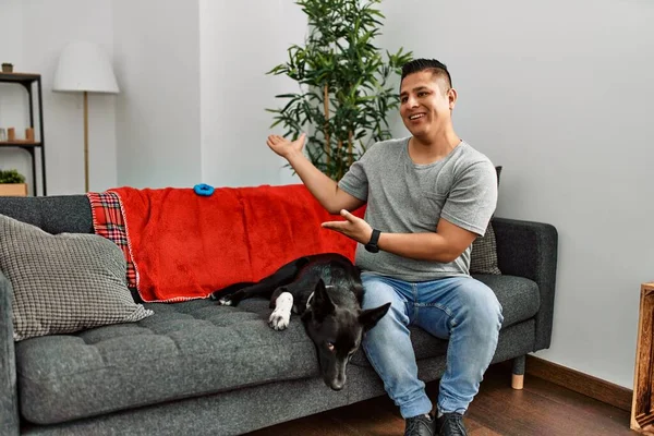 Jovem Latino Homem Cão Sentado Sofá Casa Convidando Para Entrar — Fotografia de Stock