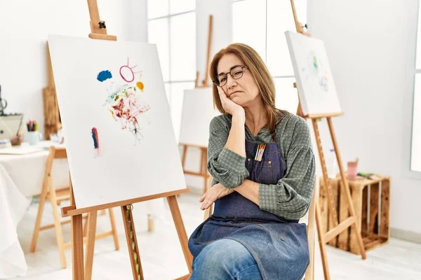 Middle age artist woman at art studio thinking looking tired and bored with depression problems with crossed arms.