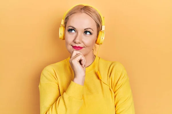 Mujer Rubia Joven Escuchando Música Usando Auriculares Con Mano Barbilla —  Fotos de Stock