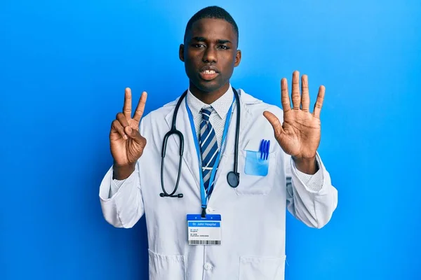 自信を持って幸せな笑顔ながら 若いアフリカ系アメリカ人男性は医師の制服を着て指の数7で示すと指摘します — ストック写真