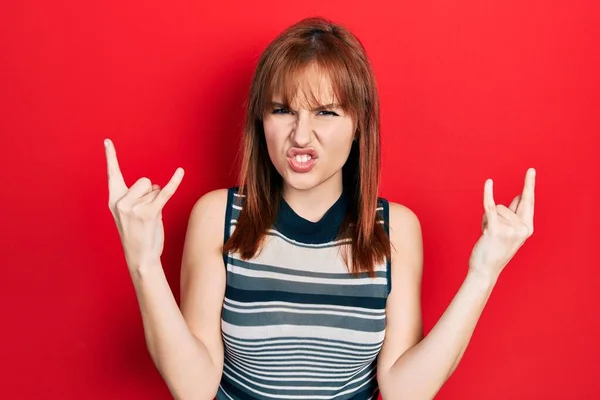 手を上げて岩のシンボルをやって狂気の表情で叫んでカジュアルなTシャツを着て若い女性をRedhead 音楽スター 重い概念は — ストック写真