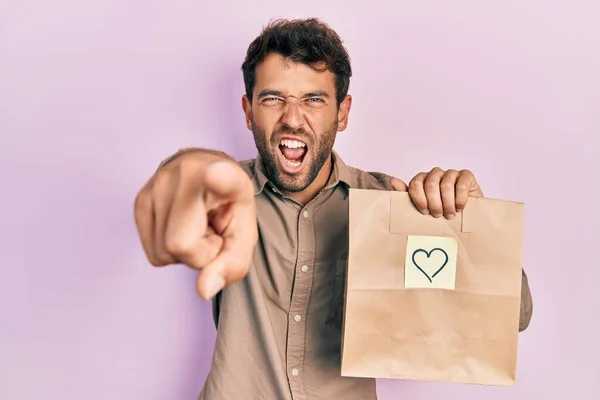 Handsome Man Beard Holding Delivery Paper Bag Heart Reminder Pointing — Stock Photo, Image