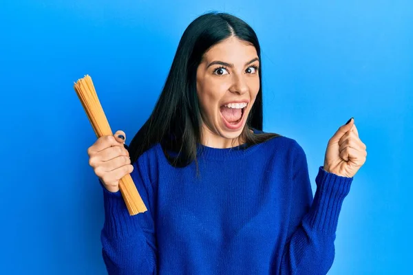 Young Hispanic Woman Holding Uncooked Spaghetti Screaming Proud Celebrating Victory — Stock Photo, Image