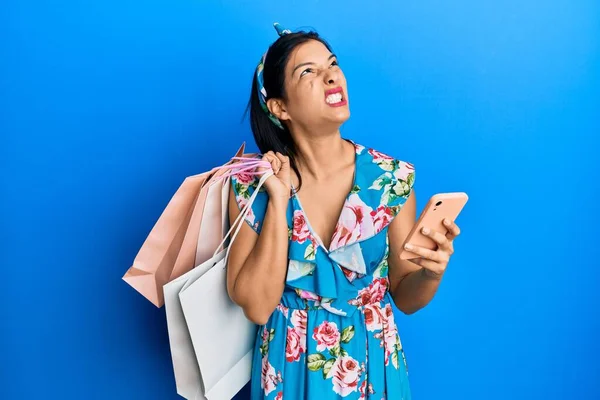 Mladá Latinská Žena Drží Nákupní Tašky Smartphone Naštvaný Šílený Křičí — Stock fotografie