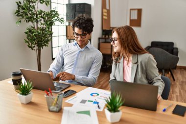 Ofiste dizüstü bilgisayarla çalışırken gülümseyen iki iş adamı..