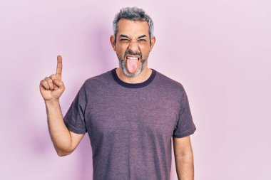 Yakışıklı, orta yaşlı, gri saçlı, işaret parmağıyla işaret eden komik bir ifadeyle dilini dışarı çıkaran adam.. 
