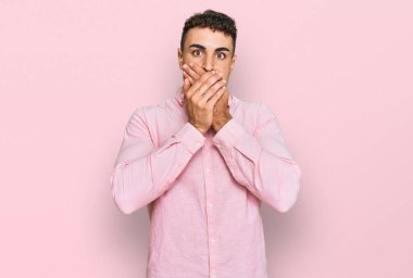 Günlük kıyafetler giyen İspanyol genç adam yanlışlıkla elleri ile ağzını kapatırken şok oldu. gizli kavram. 