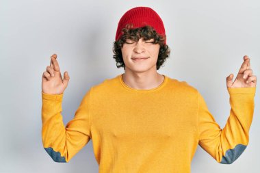 Yün şapka takan yakışıklı genç adam umut ve gözlerin kapalı gülümseyerek işaret ediyor. Şans ve batıl inançlar. 