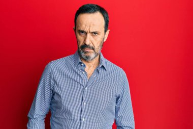 Orta yaşlı İspanyol bir adam gündelik kıyafetler giyiyor şüpheci ve gergin, sorun yüzünden surat asıyor. negatif kişi. 