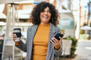 Genç İspanyol iş kadını akıllı telefon kullanıyor. Şehirde kahve içiyor..