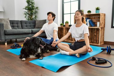 Kafkasyalı genç çift evde köpekle yoga eğitimine konsantre oluyor..