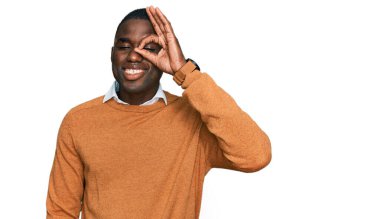 Genç Afro-Amerikan adam günlük kıyafetler giyiyor gülümsüyor mutlu bir şekilde el pençe divan duruyor. 