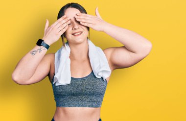 Spor kıyafetleri ve havluyla gözlerini kapayan neşeli ve komik gülümseyen genç İspanyol kız. kör kavram. 