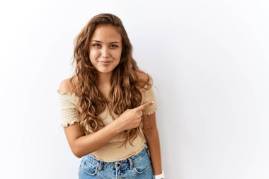 Yüzünde mutlu ve doğal bir ifade olan, elleri ve parmaklarıyla yüzünü gösteren bir tebessümle arka planda tek başına duran güzel İspanyol kadın. 