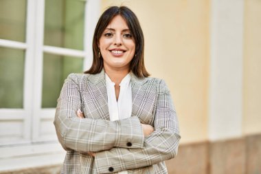 Genç İspanyol iş kadını şehirde çapraz hareketlerle mutlu gülümsüyor..