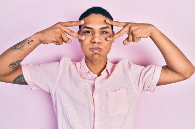 Genç Afro-Amerikalı adam zafer işareti yapıyor ve barış jesti komik suratıyla yanakları şişiriyor. Ağzı havayla şişer, havayı yakalar.. 