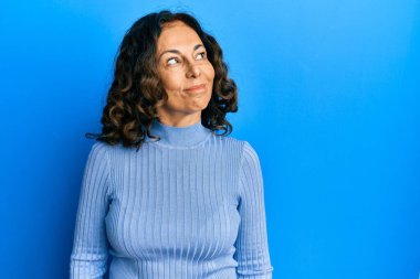 Orta yaşlı İspanyol kadın gündelik kıyafetler giyiyor gülümsüyor yan tarafa bakıyor ve düşünüyor.. 