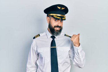 Genç İspanyol pilot üniforması giyen mutlu yüzüyle gülümseyen ve başparmağıyla yan tarafı gösteren.. 