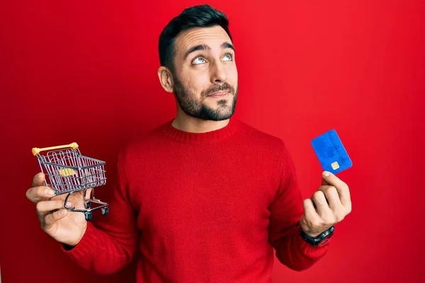 Молодий Іспаномовний Чоловік Тримає Маленький Супермаркет Кошик Кредитну Картку Посміхаючись — стокове фото