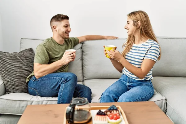 Jovem Casal Hispânico Sorrindo Feliz Tomando Café Manhã Sentado Sofá — Fotografia de Stock