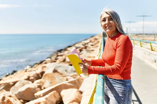 Medelålders Gråhårig Kvinna Ler Glad Läsning Bok Stranden — Stockfoto